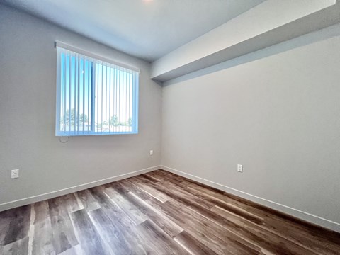 A room with a window and wooden flooring.
