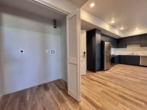 A kitchen with a refrigerator and cabinets in a room with wooden flooring.