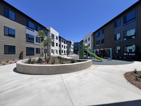 A playground with a slide is in front of a building.