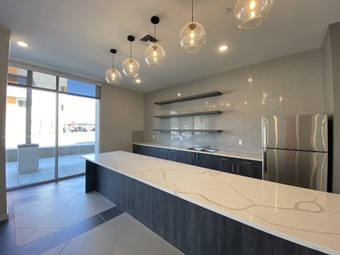 a kitchen with a long counter top and a stainless steel refrigerator