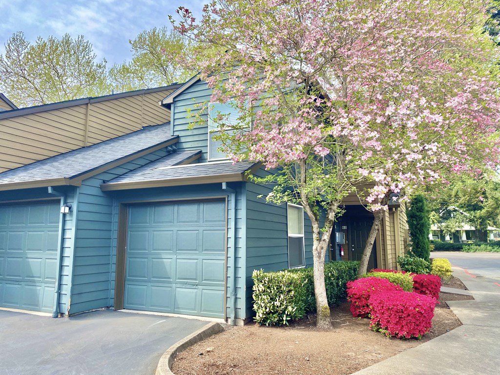 a blue house with blue garage doors and a flowering tree