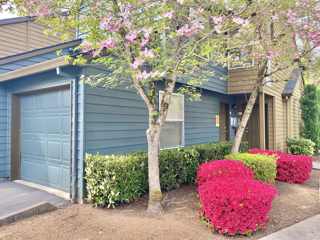 a blue house with a blue garage door and pink flowers