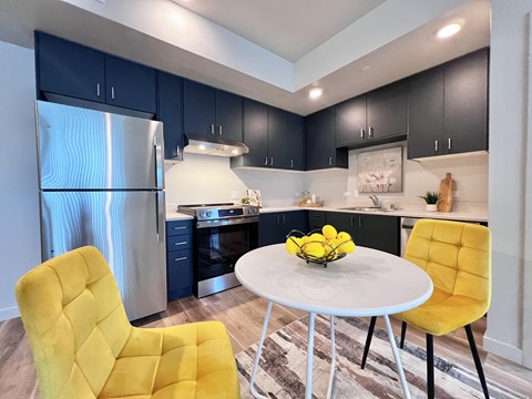 A modern kitchen with a yellow chair and a white table.