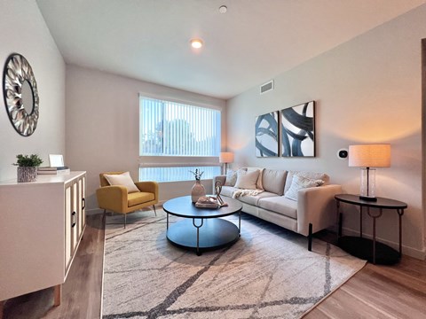 A living room with a yellow chair, a white couch, and a round coffee table.