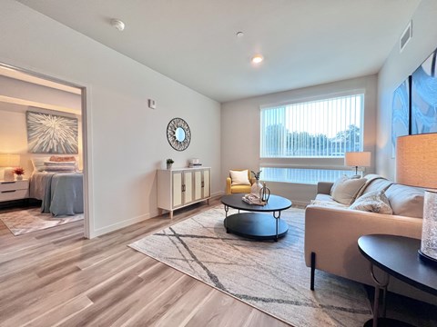 A modern living room with a grey sofa, a round coffee table, and a large window.
