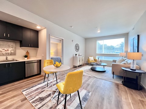 A modern kitchen with a yellow chair and a dining table.
