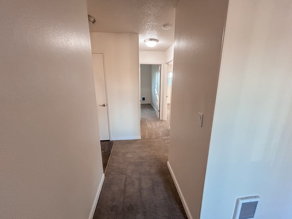 A long hallway with a door on the left and a window on the right.