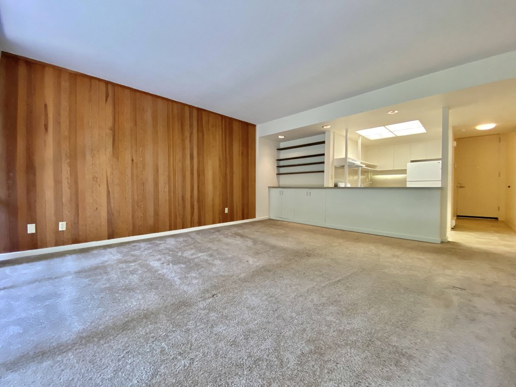the living room and kitchen of a house with a concrete floor and wooden walls