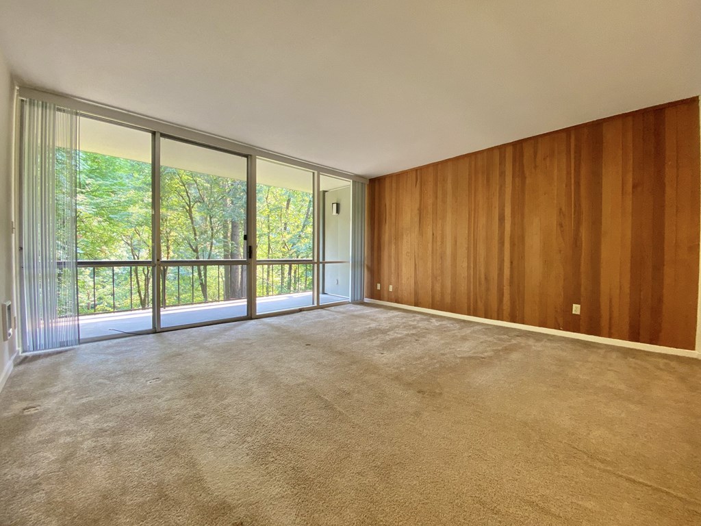 an empty living room with wood paneling and a balcony