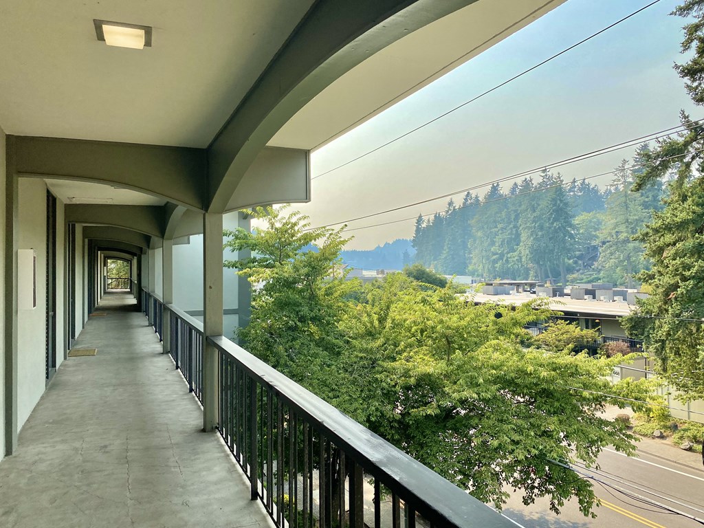 a long balcony with a view of trees and a highway