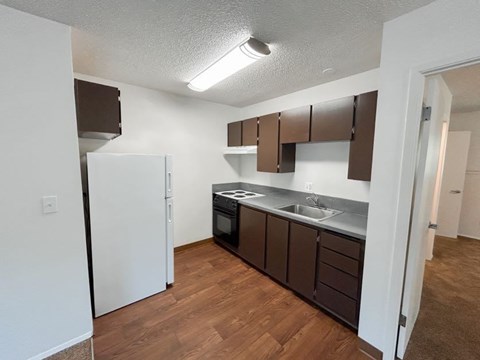 A kitchen with brown cabinets and a white refrigerator.