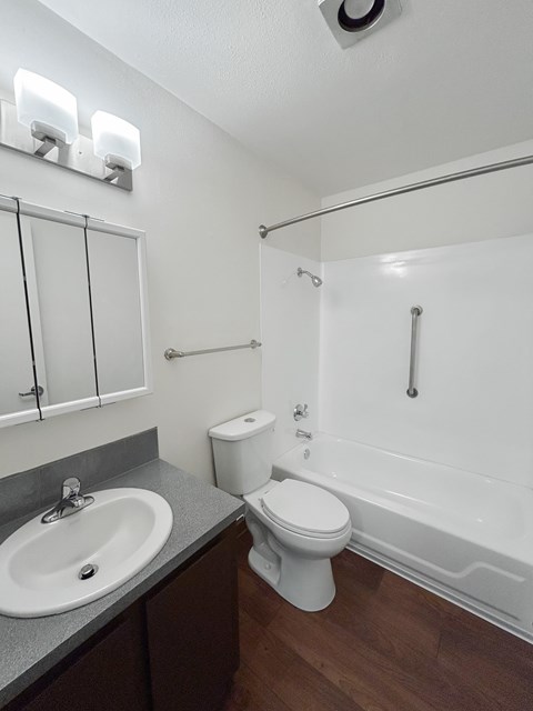 A white toilet sits next to a white bathtub in a bathroom.