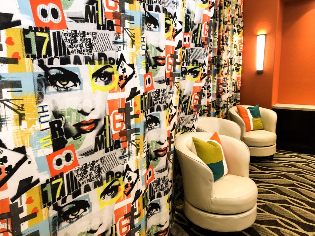 a room with two white chairs and a curtain with faces on it