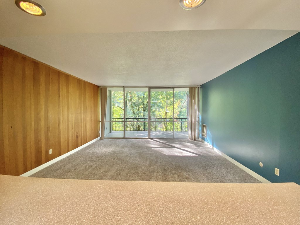 an empty living room with a balcony and blue walls and carpet