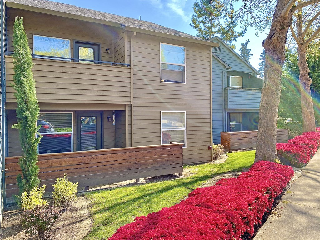 the front of a house with a wooden bench and red flowers