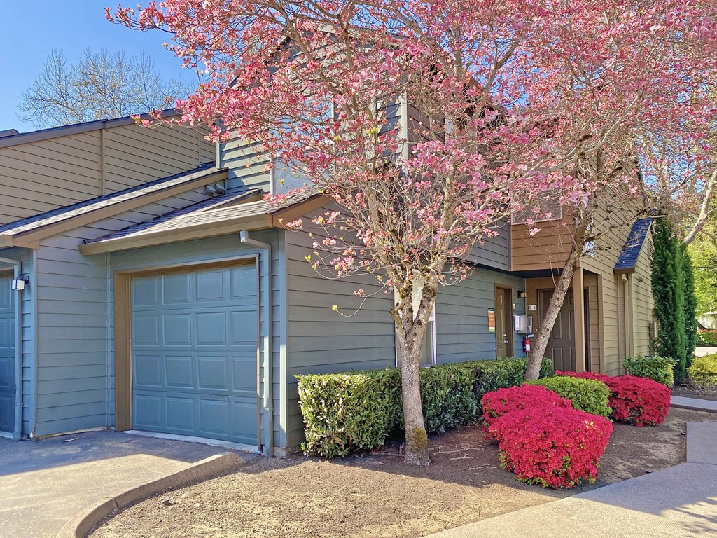 a house with a blue garage door and a tree with pink flowers