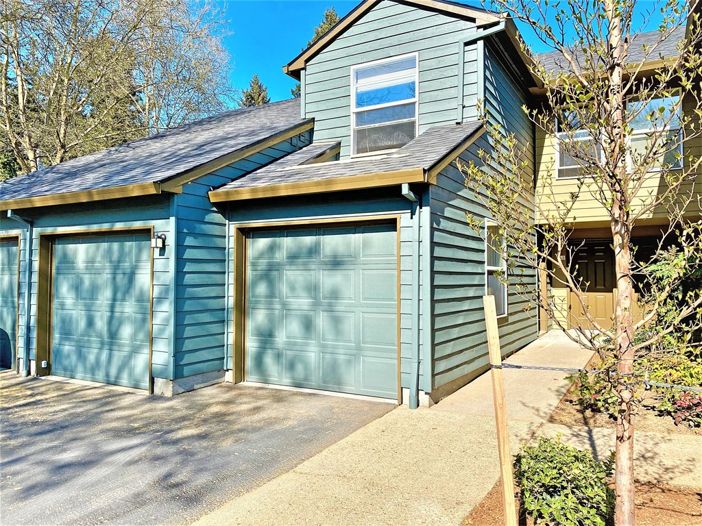 a blue garage with a blue house with two garage doors