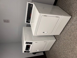 Two white air conditioners are stacked on top of each other.