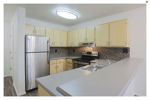a kitchen with white counter tops and a stainless steel refrigerator