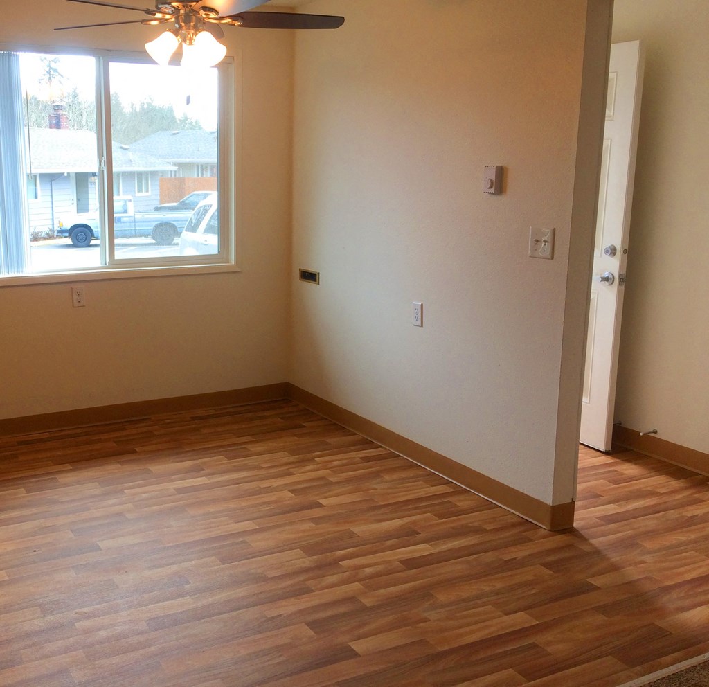 an empty living room with wooden floors and a window