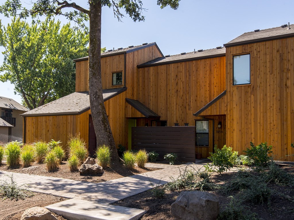 a wooden house with a walkway and a tree