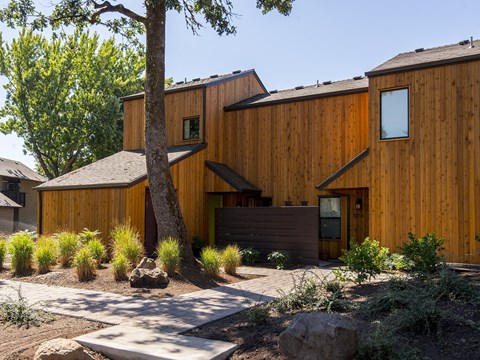 a wooden house with a walkway and a tree