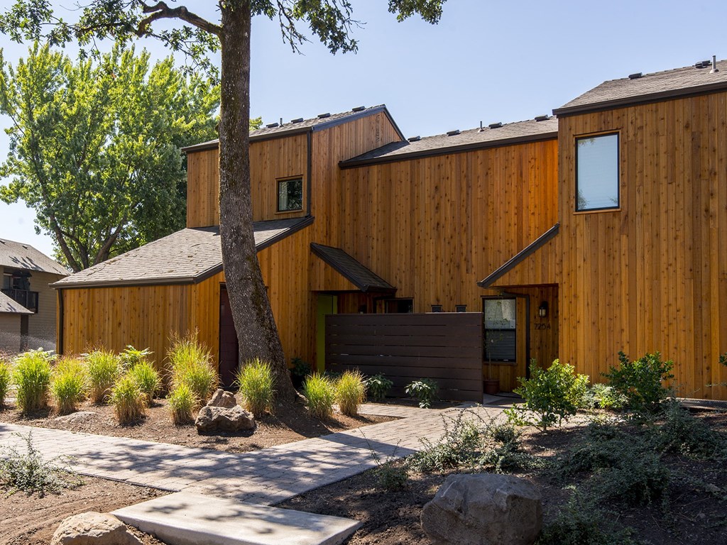 a wooden house with a walkway and a tree