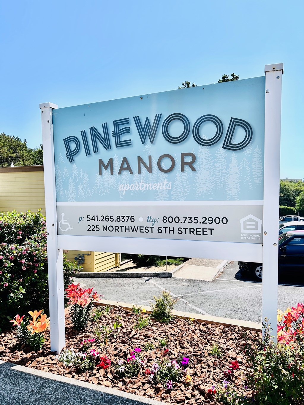 A sign for Pinewood Manor apartments with a phone number and address.