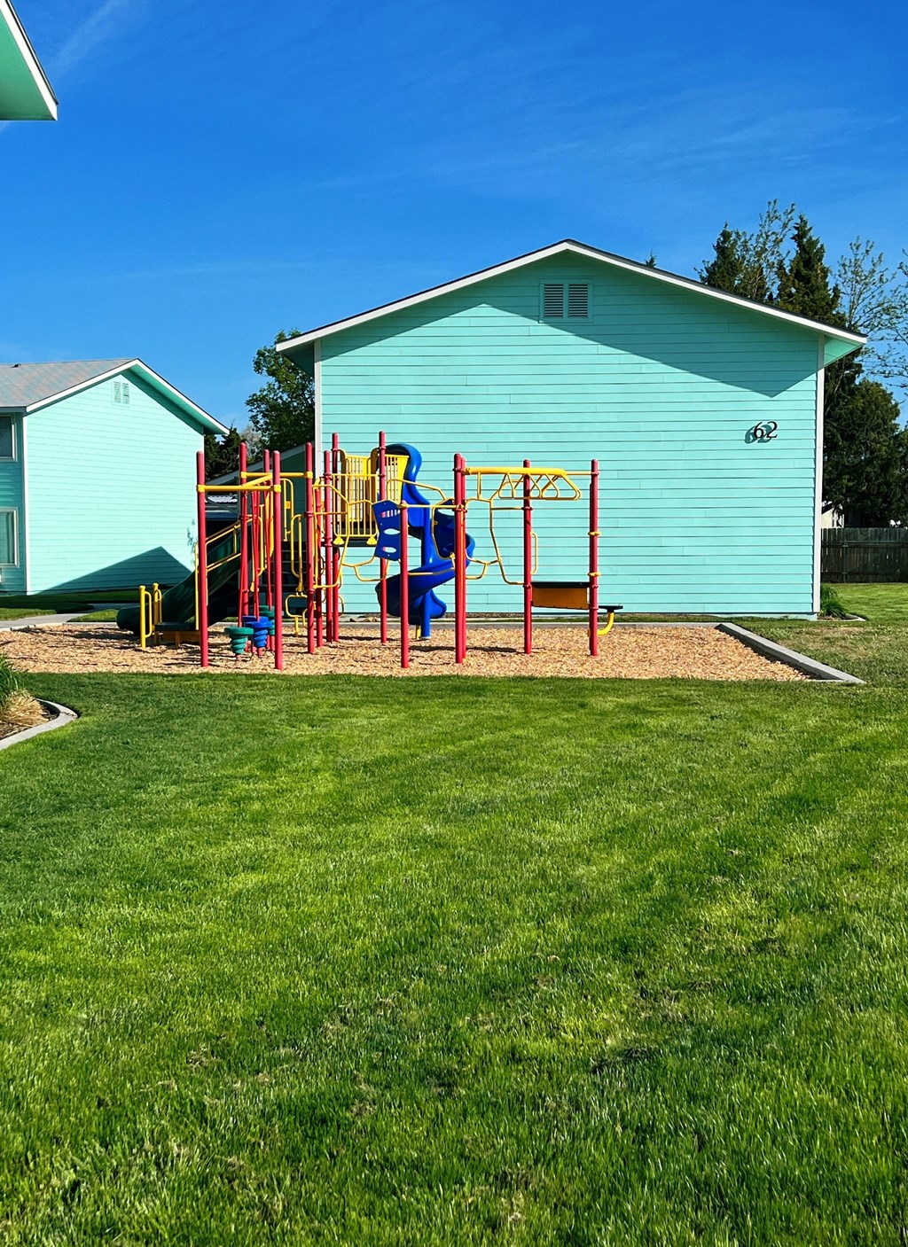 a playground in a yard in front of a blue building