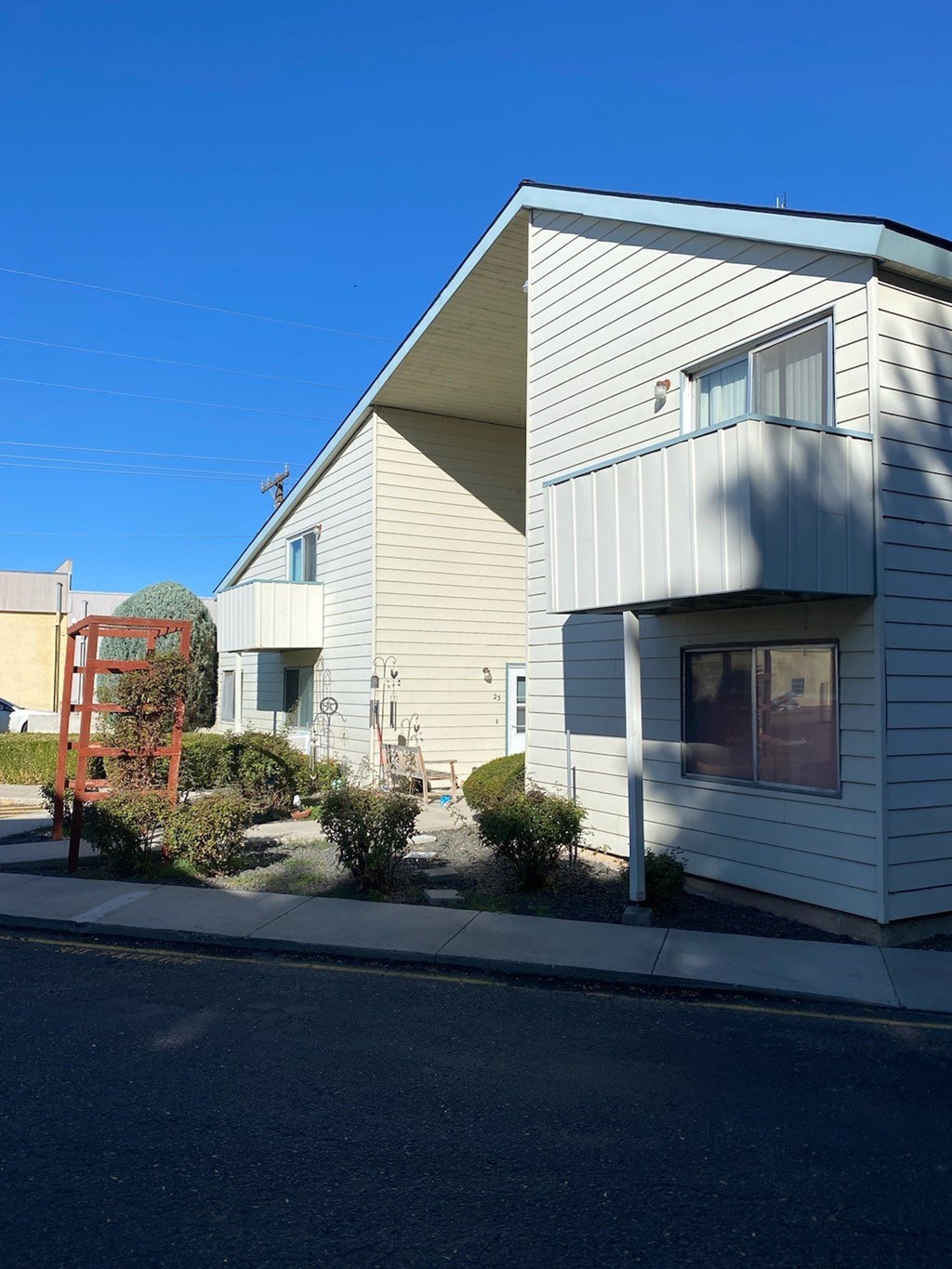 A house with a white siding and a red chair in front of it.