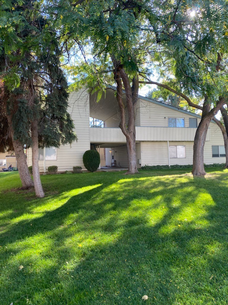 A house with a green lawn and trees in front.