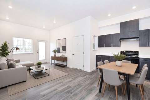 A modern living room with a grey sofa, a coffee table, and a dining table with grey chairs.