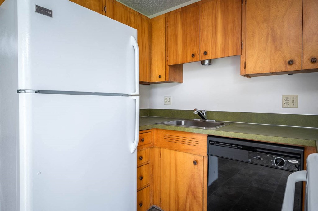 a kitchen with a white refrigerator freezer next to a dishwasher