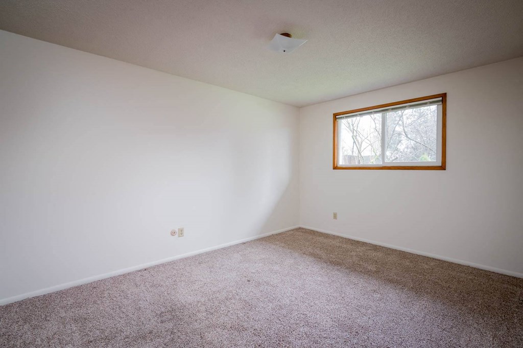 a bedroom with white walls and a window