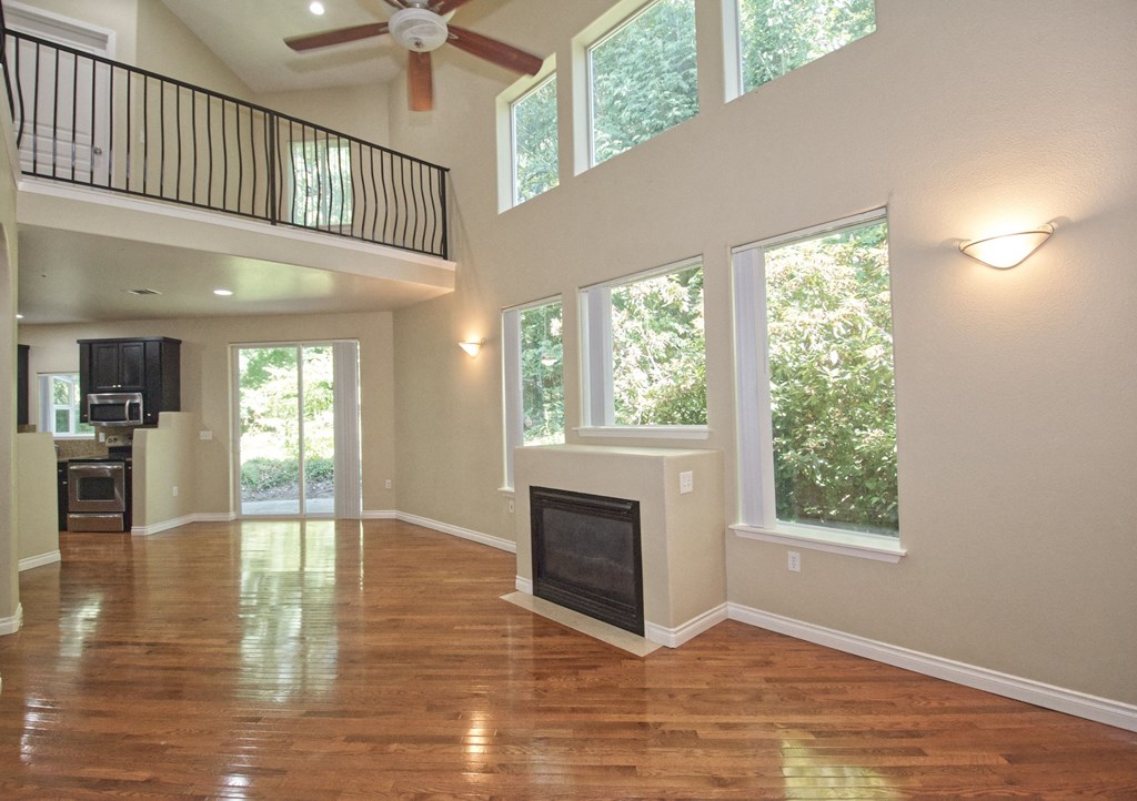 an empty living room with a fireplace and large windows