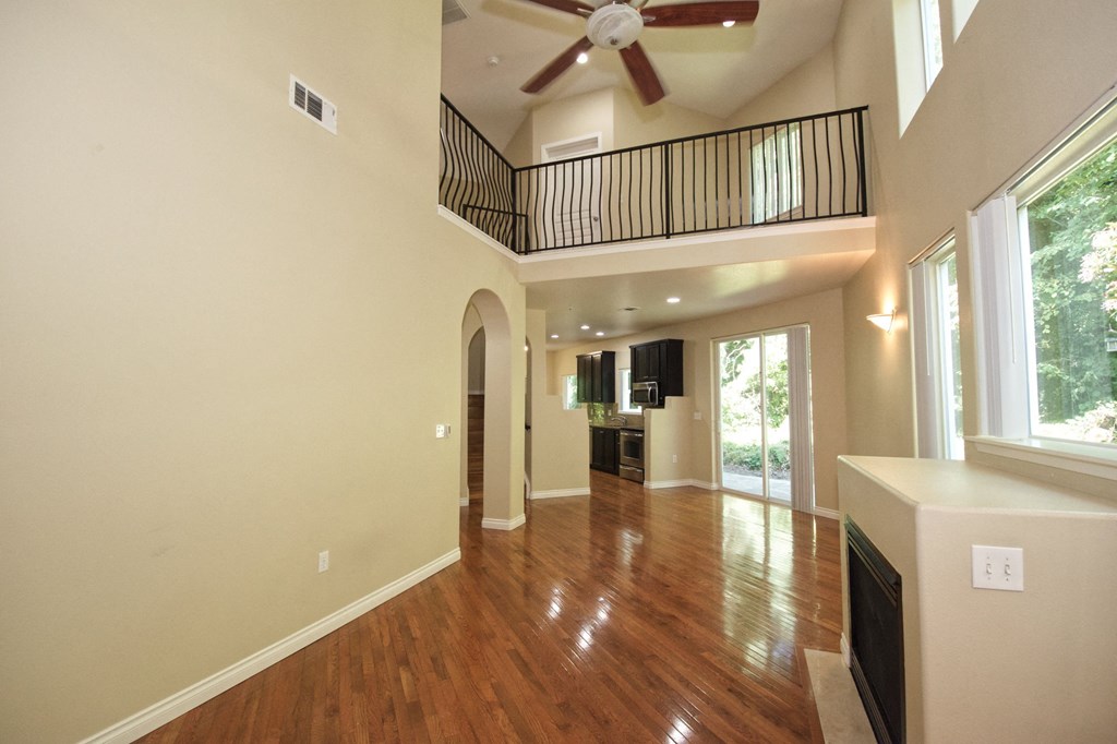 an open living room with a ceiling fan and a balcony