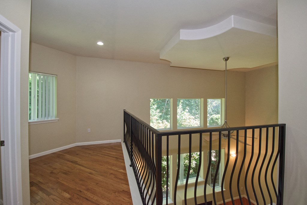 the view from the top of a staircase in a home with windows and wood floors