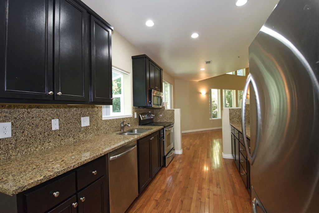 a kitchen with black cabinets and a stainless steel refrigerator