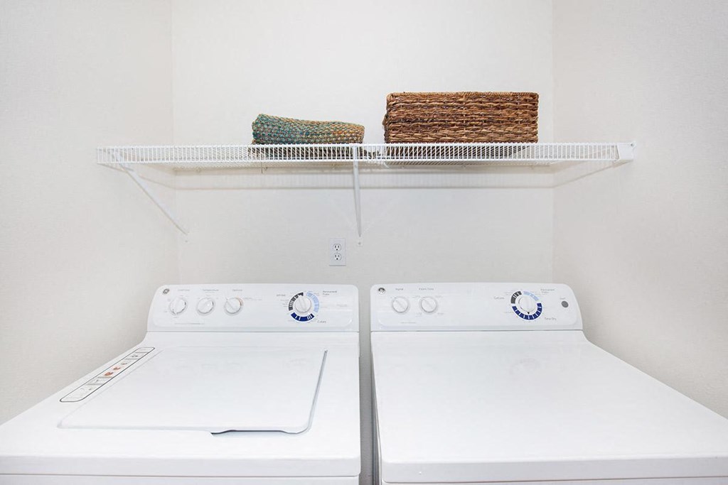 a white laundry room with two washers and a dryer