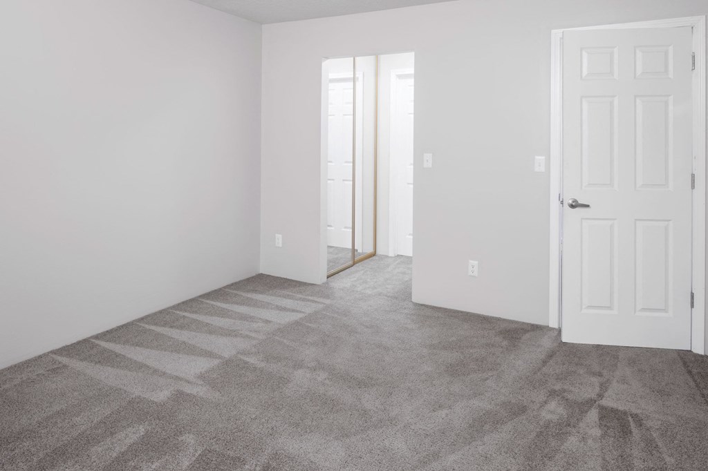 a bedroom with a white door and gray carpet
