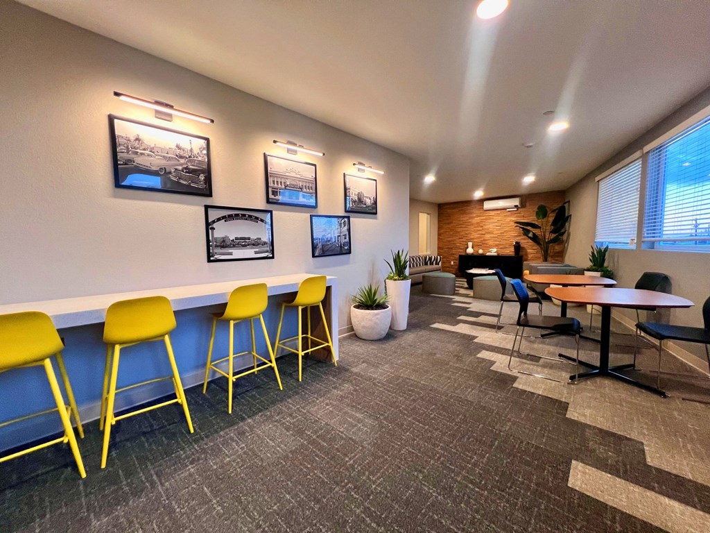 a lounge area with yellow chairs and tables and a piano