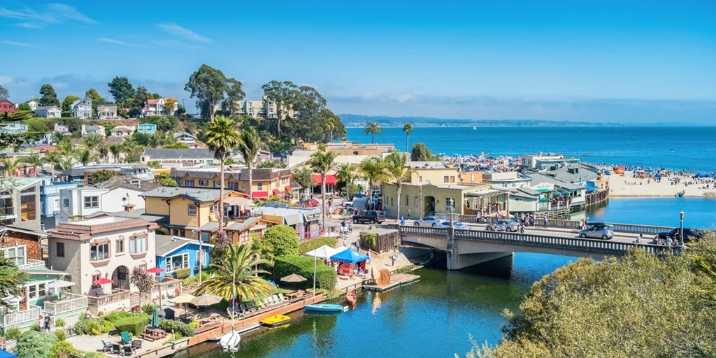 A coastal town with a bridge over a river and palm trees.