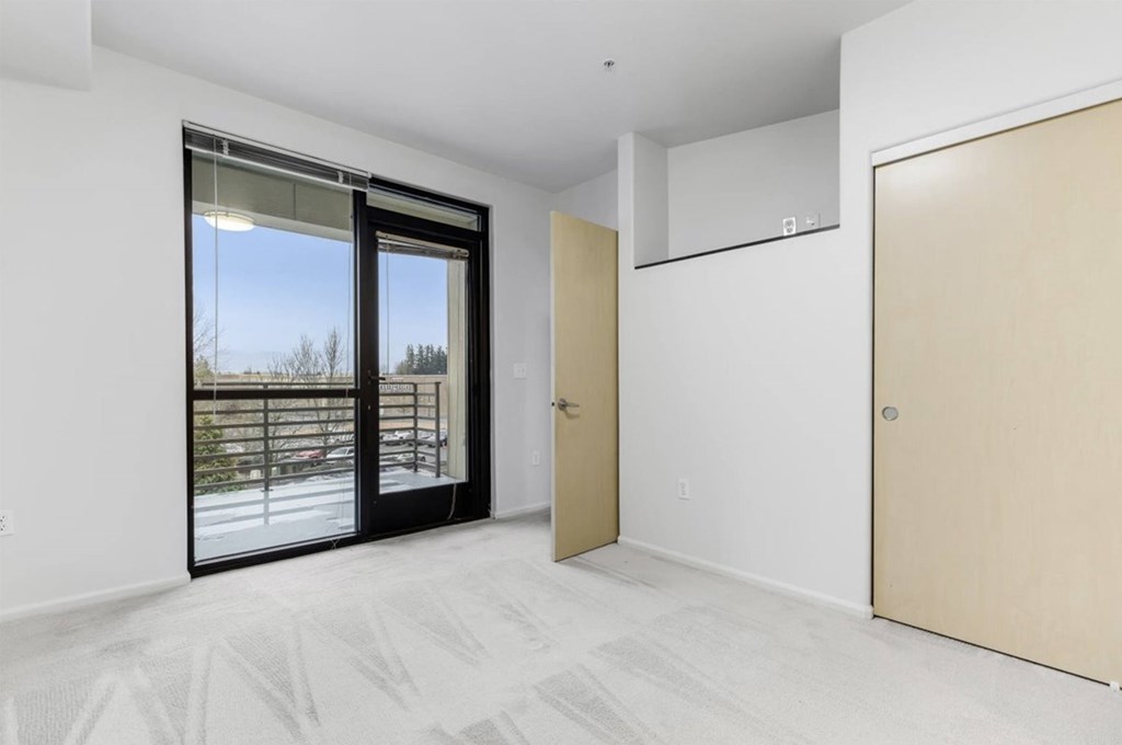 A room with a sliding glass door and a wooden door.
