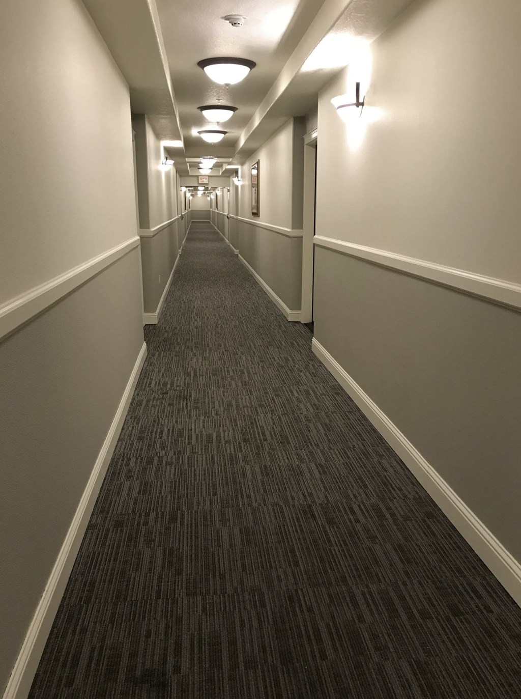 A long hallway with carpeted floors and white walls.