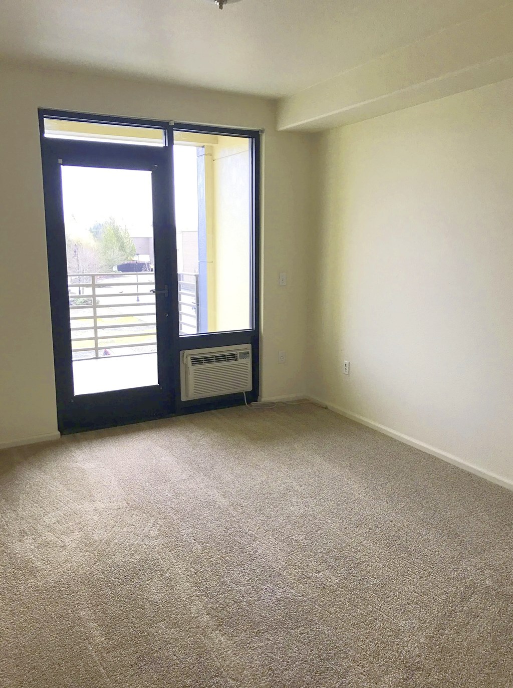 A room with a carpeted floor and a sliding glass door.