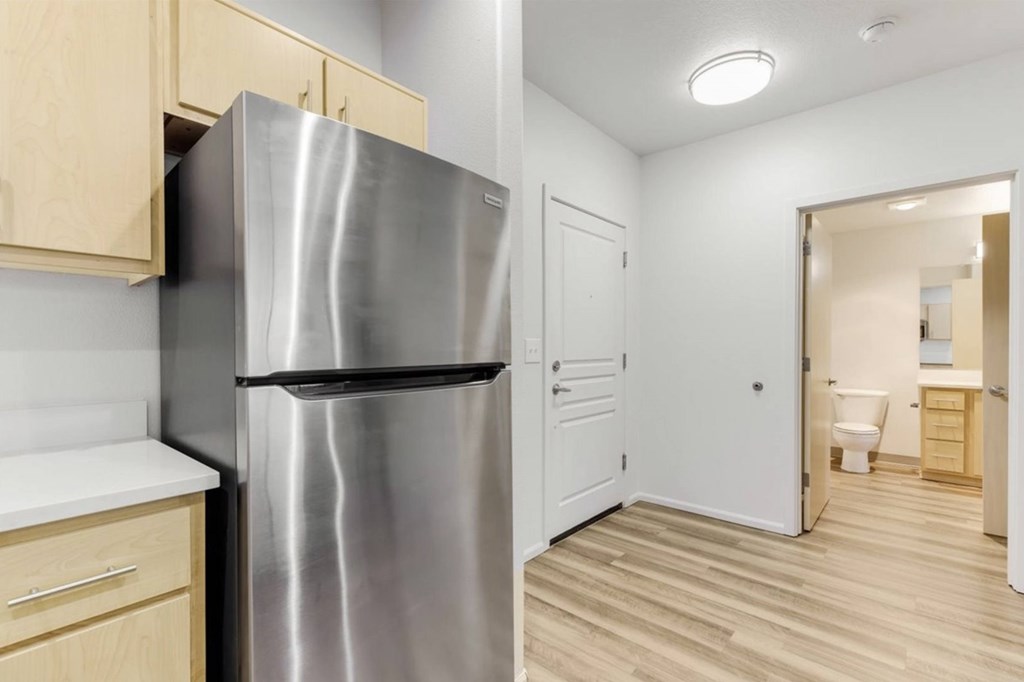 A kitchen with a stainless steel refrigerator and wooden cabinets.