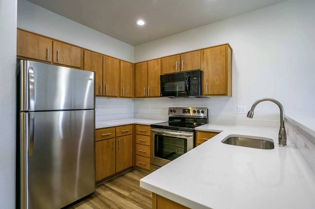 A kitchen with a stainless steel refrigerator, microwave, oven, and sink.