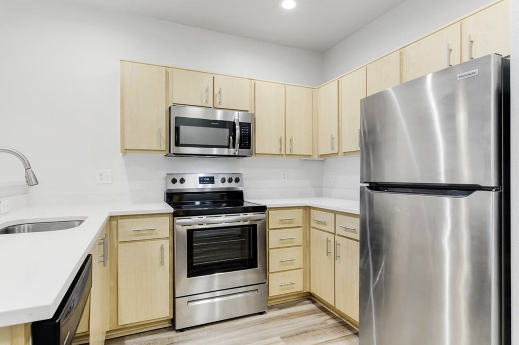 A kitchen with a stainless steel refrigerator, microwave, oven, and sink.