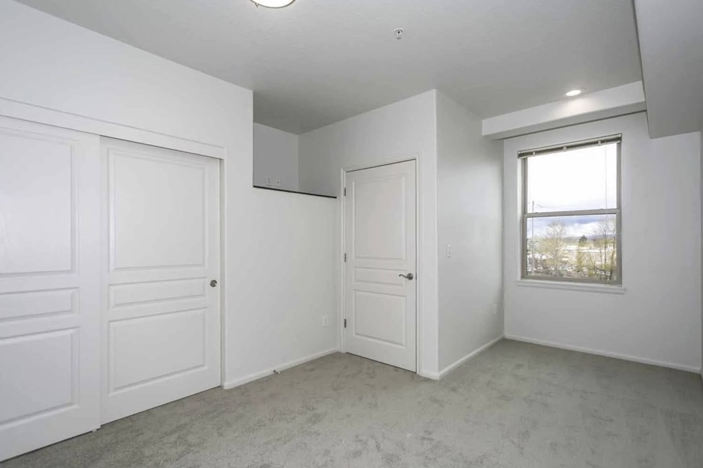 A white room with a door, a window, and a ceiling light.