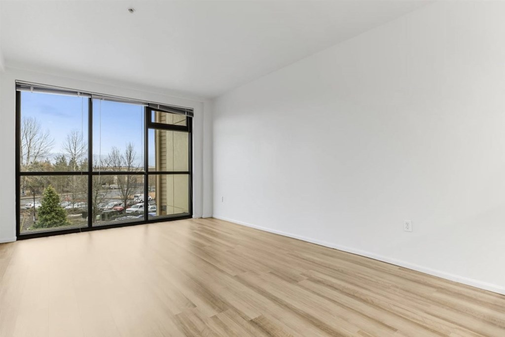 A room with a large window and wooden flooring.